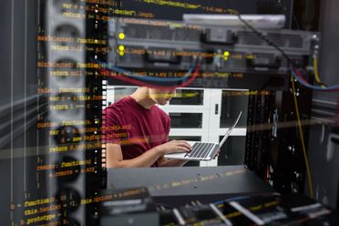 Ein Mitarbeiter arbeitet an einem Laptop vor einem Server-Rack, das Teil des KI-Servers von Thomas-Krenn.AG ist.