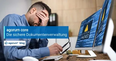 Ein Mitarbeiter mit Kopfschmerzen blickt auf einen gehackten Computer. Datenverlust und Sicherheitslücken bedrohen die Geschäftsprozesse und die Digitalisierung im Unternehmen.