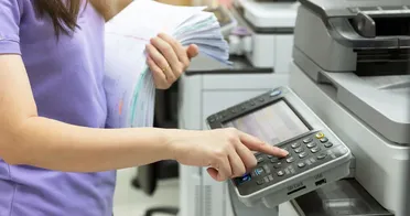 Frau scannt Papierstapel mit dem Multifunktionsdrucker für die automatische Sortierung im Dokumentenmanagement System.
