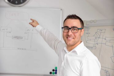 Ein Mitarbeiter von BES IT Solutions zeigt auf ein Whiteboard mit strategischen Diagrammen während eines Strategie-Workshops.